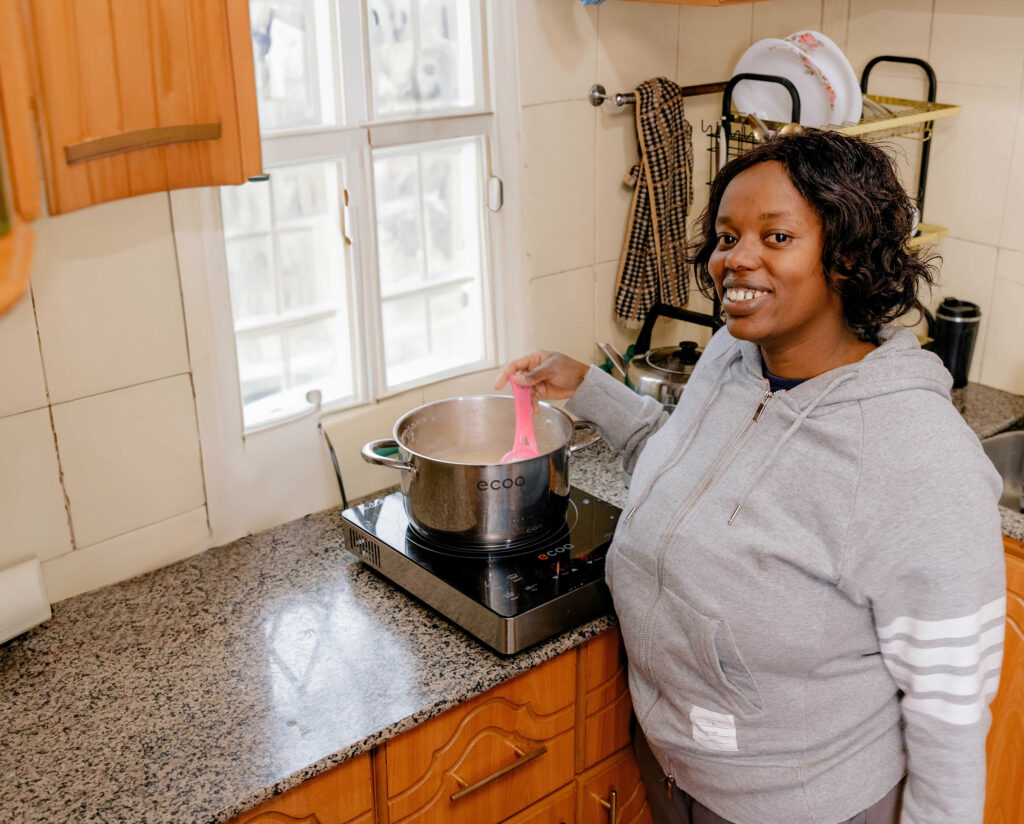 Photo: A woman in Kenya cooking food on an electric induction cooker – BURN